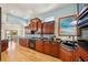 Cherry wood kitchen featuring black countertops, stainless steel appliances, an open floorplan, and hardwood floors at 6543 Louise Ct, Hudson, FL 34667
