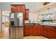Modern kitchen with stainless steel refrigerator, cherry wood cabinetry, black countertops, and view to living area at 6543 Louise Ct, Hudson, FL 34667