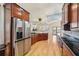 Modern kitchen with stainless steel refrigerator, cherry wood cabinetry, black countertops, and hard wood flooring at 6543 Louise Ct, Hudson, FL 34667