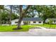 Charming single-story home with a manicured lawn, mature trees and bright yellow front door at 6921 N 16Th St, Tampa, FL 33610