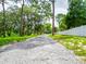 Long gravel driveway leading to a charming home, surrounded by lush greenery and a white fence at 7211 Red Oak Loop, New Port Richey, FL 34654