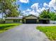 Charming single-story home featuring a stone accent garage and long driveway and lush front yard at 7211 Red Oak Loop, New Port Richey, FL 34654