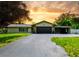 Charming single-story home with a welcoming driveway, lush lawn, and well-manicured landscaping under a beautiful sunset at 7211 Red Oak Loop, New Port Richey, FL 34654