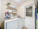 Functional laundry area with washer, dryer, storage shelves, and convenient access to the outdoors at 7211 Red Oak Loop, New Port Richey, FL 34654
