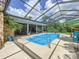 Inviting swimming pool in a screened enclosure with tropical landscaping at 7211 Red Oak Loop, New Port Richey, FL 34654