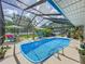 Refreshing screened-in pool with ample lounging space and lush landscaping, perfect for outdoor relaxation and entertaining at 7211 Red Oak Loop, New Port Richey, FL 34654
