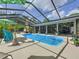 Sparkling swimming pool in screened enclosure with tropical landscaping at 7211 Red Oak Loop, New Port Richey, FL 34654