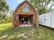 Open doors reveal the shed's interior, filled with storage, tools, and workspace on a concrete floor at 7211 Red Oak Loop, New Port Richey, FL 34654