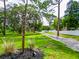 View of the street number marker along a long driveway, lush greenery, and white fencing at 7211 Red Oak Loop, New Port Richey, FL 34654