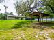 Expansive green lawn with mature trees surrounding a charming home and covered outdoor structure at 7211 Red Oak Loop, New Port Richey, FL 34654