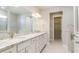 Bright bathroom featuring double sinks, granite counters, decorative tile, and a door to the walk-in closet at 7621 Highgrove Ave, Bradenton, FL 34210