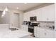 Well-appointed kitchen with white cabinets, stainless steel appliances and a granite-topped island with a double sink at 7621 Highgrove Ave, Bradenton, FL 34210