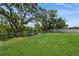 Expansive backyard with lush green grass and a view of the canal with mature trees at 9107 Brunswick Ln, Tampa, FL 33615