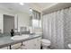 Clean bathroom with a patterned shower curtain, toilet, and single sink with a mirrored backsplash at 9619 Towanda Ln, Port Richey, FL 34668
