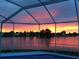 Tranquil sunset view from a screened-in porch overlooking a serene lake at twilight at 9619 Towanda Ln, Port Richey, FL 34668