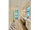 Bright bathroom featuring a dual vanity with white cabinets and walk-in glass shower at 10864 Banyan Breeze Blvd, Land O Lakes, FL 34638