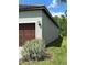 Exterior side view of attached two-car garage with manicured landscaping at 10864 Banyan Breeze Blvd, Land O Lakes, FL 34638