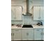 White kitchen with quartz counters, stainless hood, electric cooktop, and bright natural light at 10864 Banyan Breeze Blvd, Land O Lakes, FL 34638
