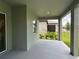 Covered patio with grey painted flooring overlooking backyard grass and manicured landscaping at 10864 Banyan Breeze Blvd, Land O Lakes, FL 34638