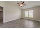 Bright bedroom with wood-look tile, ceiling fan, and a large window providing natural light at 10915 Kirkwall Port Dr, Wimauma, FL 33598