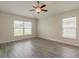 Bedroom with wood-look tile flooring, two windows, and a ceiling fan at 10915 Kirkwall Port Dr, Wimauma, FL 33598
