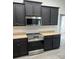 Modern kitchen features stainless steel appliances and dark cabinets against beautiful tile floors at 10915 Kirkwall Port Dr, Wimauma, FL 33598