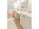 Bright bathroom with double sinks, white cabinets and pink tiled wall and backsplash at 113 Maplewood Ave, Clearwater, FL 33765