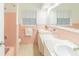 Bright bathroom with double sinks, white cabinets and pink tiled walls and backsplash at 113 Maplewood Ave, Clearwater, FL 33765