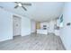 Open-concept living room with modern gray wood floors flowing into the kitchen with white cabinets at 11619 Cambium Crown Dr, Riverview, FL 33569