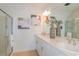 Bright bathroom featuring double sinks, white cabinets, stylish decor, and a glass-enclosed shower at 13548 Tropical Breeze Way, Hudson, FL 34669