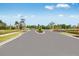Palm Wind community entrance with fresh landscaping, smooth black roads, and swaying palm trees at 13548 Tropical Breeze Way, Hudson, FL 34669