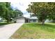Traditional-style home featuring a two-car garage, manicured lawn, and a welcoming entrance amidst mature trees at 1461 S Hillcrest Ave, Clearwater, FL 33756