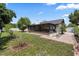 Landscaped backyard features a screened-in patio, established trees, and manicured lawn at 15012 Winterwind Dr, Tampa, FL 33624