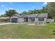 Charming home featuring black trim, a gray garage door, and a well-manicured front lawn at 15012 Winterwind Dr, Tampa, FL 33624