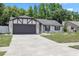 Charming home featuring black trim, a gray garage door, and a well-manicured front lawn at 15012 Winterwind Dr, Tampa, FL 33624