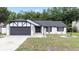 Charming home featuring black trim, a gray garage door, and a well-manicured front lawn at 15012 Winterwind Dr, Tampa, FL 33624