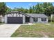 Charming home featuring black trim, a gray garage door, and a well-manicured front lawn at 15012 Winterwind Dr, Tampa, FL 33624