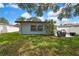 House exterior with well-maintained lawn, mature trees and a grill on the patio at 1809 Chinaberry Dr, Oldsmar, FL 34677