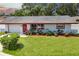 Charming single-story home featuring a red door, vibrant landscaping, and a well-manicured front lawn at 1809 Chinaberry Dr, Oldsmar, FL 34677