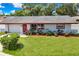 A cozy single-Gathering home with a lush green lawn and a welcoming front door with wreath at 1809 Chinaberry Dr, Oldsmar, FL 34677