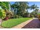 Lush tropical backyard featuring brick path, vibrant plants and an outdoor storage shed at 200 Lamara Ne Way, St Petersburg, FL 33704