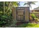Outdoor shed featuring neutral-toned paint and dark brown trim, complemented by lush foliage and grass at 200 Lamara Ne Way, St Petersburg, FL 33704