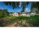 A spacious backyard showing the home's exterior, featuring grass and trees at 2003 Whispering Pines St, Largo, FL 33774