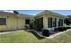 The back exterior features a sunroom, mature landscaping, and a well-manicured lawn at 205 Strong Bow Ct, Sun City Center, FL 33573