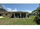 The back exterior features a sunroom, mature landscaping, and a well-manicured lawn at 205 Strong Bow Ct, Sun City Center, FL 33573