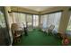A sunroom with a green carpet, wicker furniture, and large windows creates a relaxing space at 205 Strong Bow Ct, Sun City Center, FL 33573