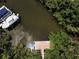 An aerial view showcases a boat dock along the canal, with trees surrounding the clear waterway at 208 Haven Beach Ct, Indian Rocks Beach, FL 33785