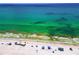 Breathtaking aerial view of a pristine beach with clear turquoise water and colorful beach umbrellas at 208 Haven Beach Ct, Indian Rocks Beach, FL 33785