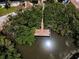 Aerial view displays a private dock surrounded by lush, green trees and sunlight reflecting off the water at 208 Haven Beach Ct, Indian Rocks Beach, FL 33785