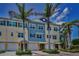 Townhouses in blue and yellow are complemented by lush landscaping and palm trees, creating a vibrant curb appeal at 208 Haven Beach Ct, Indian Rocks Beach, FL 33785